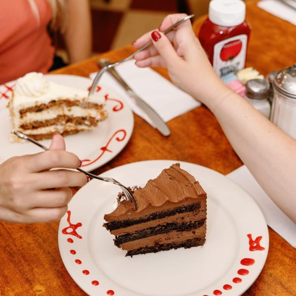 Two people sharing slices of chocolate and carrot cake at Remedy Diner.
