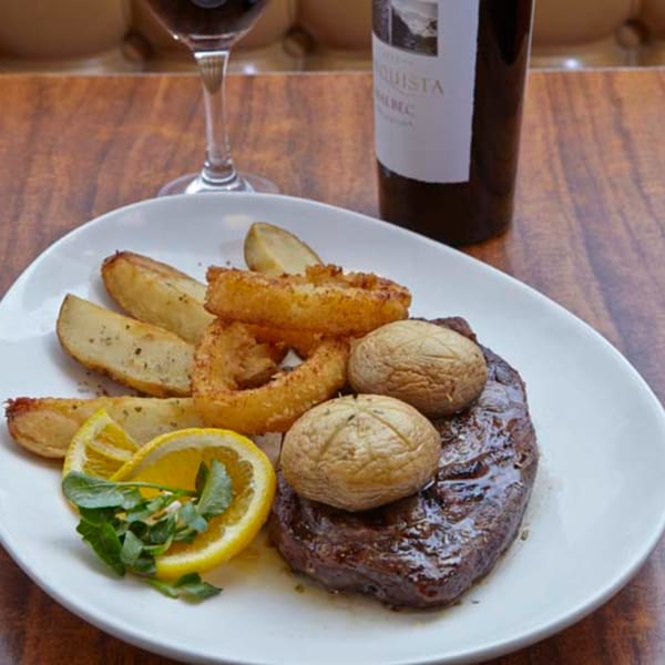 Remedy Diner's steak dinner with roasted potatoes, onion rings, lemon, and a bottle of wine.