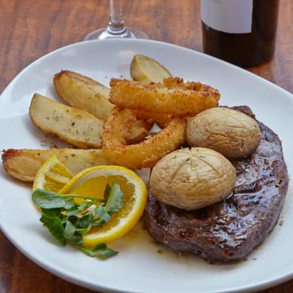 Remedy Diner's steak dinner with roasted potatoes, onion rings, mushrooms, lemon, and greens.