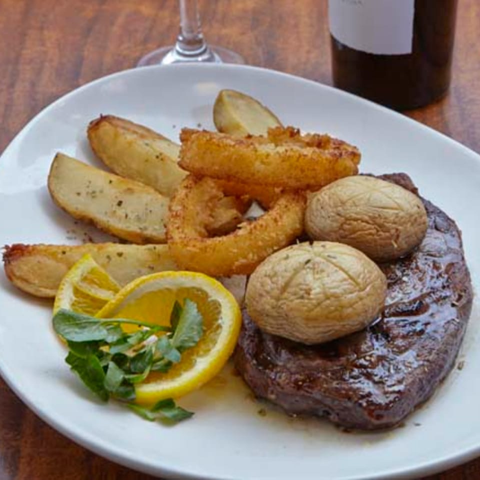 Remedy Diner's steak dinner with roasted potatoes, onion rings, mushrooms, lemon, and greens.