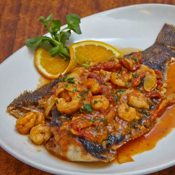 Remedy Diner's whole fish dish topped with shrimp, tomato sauce, orange slices, and greens.