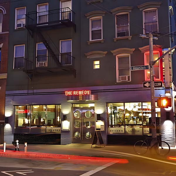 The Remedy Diner exterior at night, with a red neon sign, streetlights, and a bicycle.