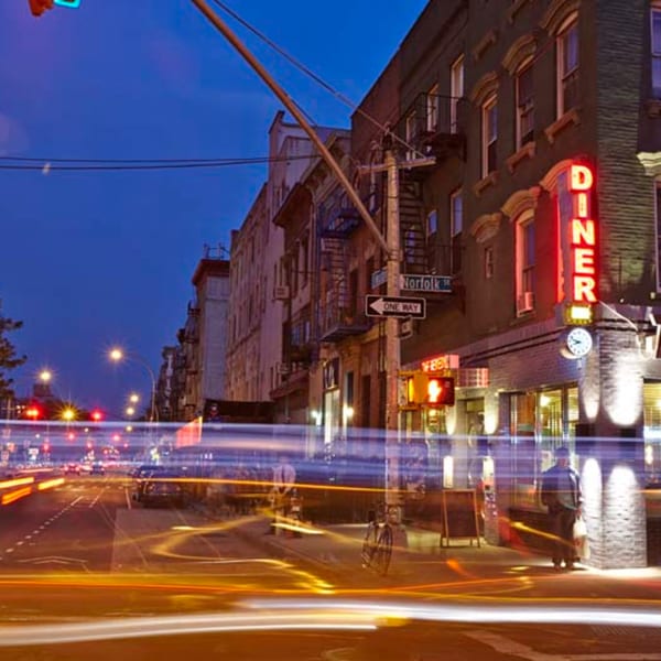 Remedy Diner at night with a bright red neon sign and blurred car lights on the street.